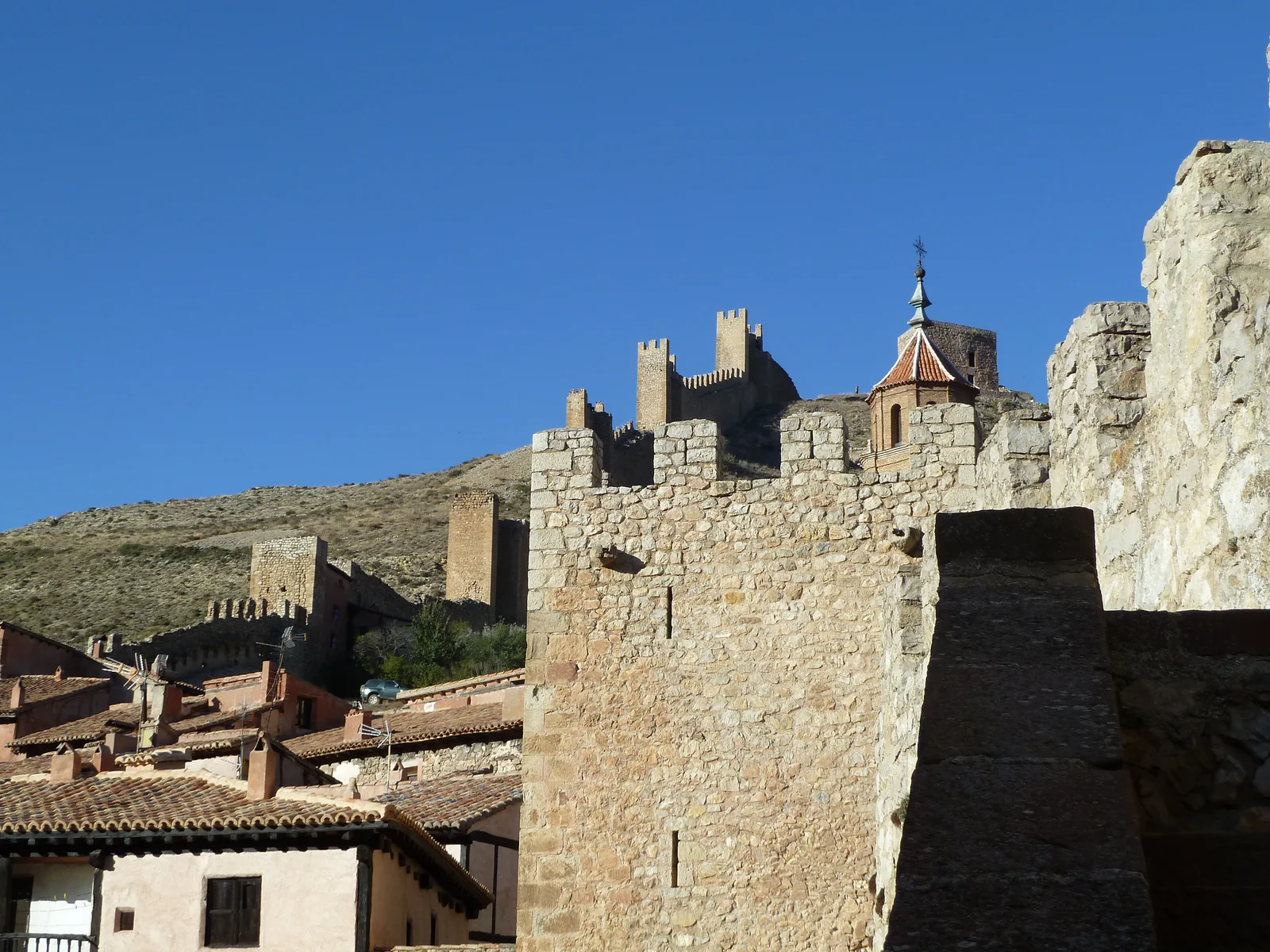 Stone battlements, tiled roofs and defensive towers climbing a bare hillside.