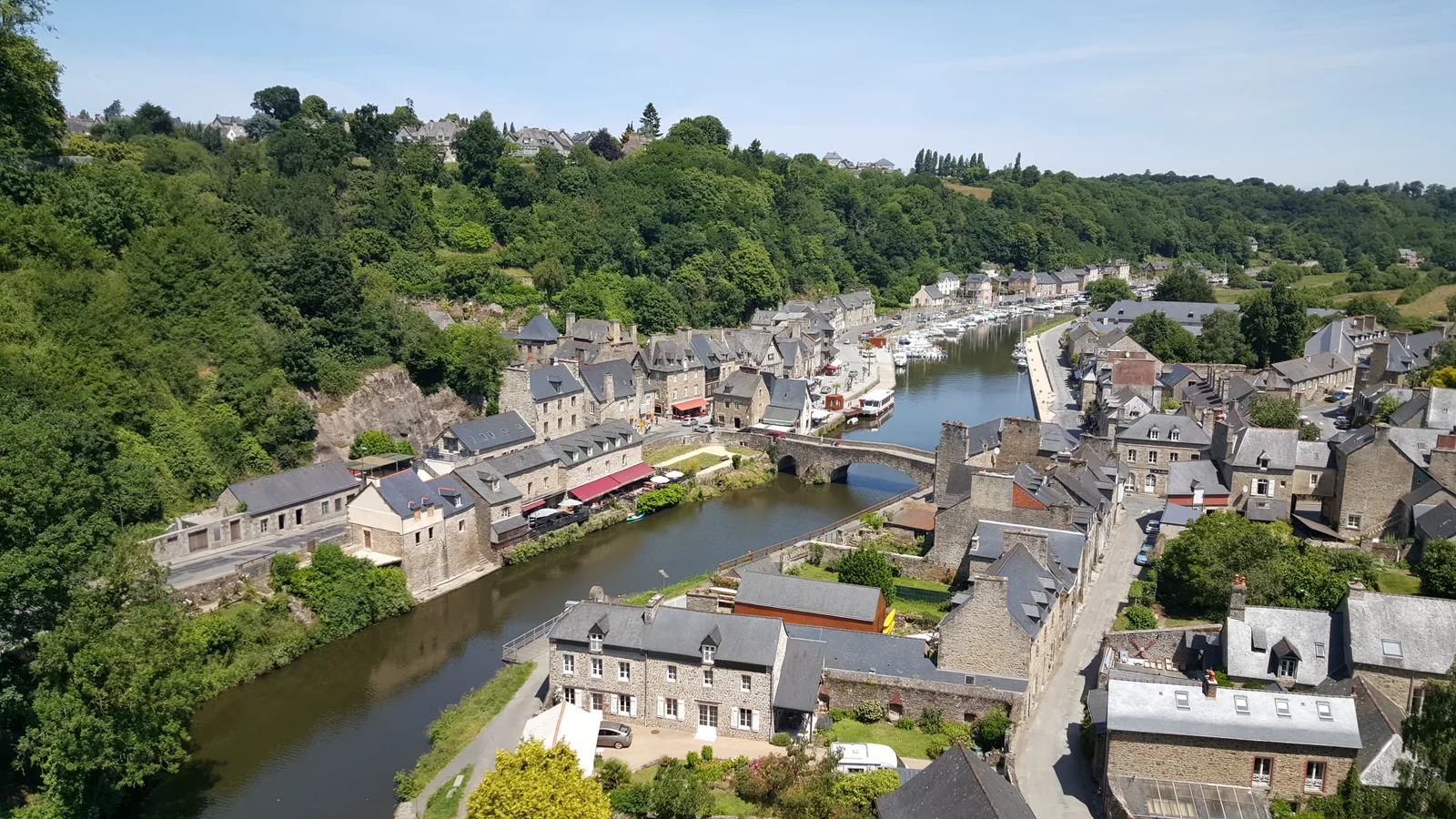 Dinan's river port, stone bridge, boats and slate-roofed houses seen from the viaduct.