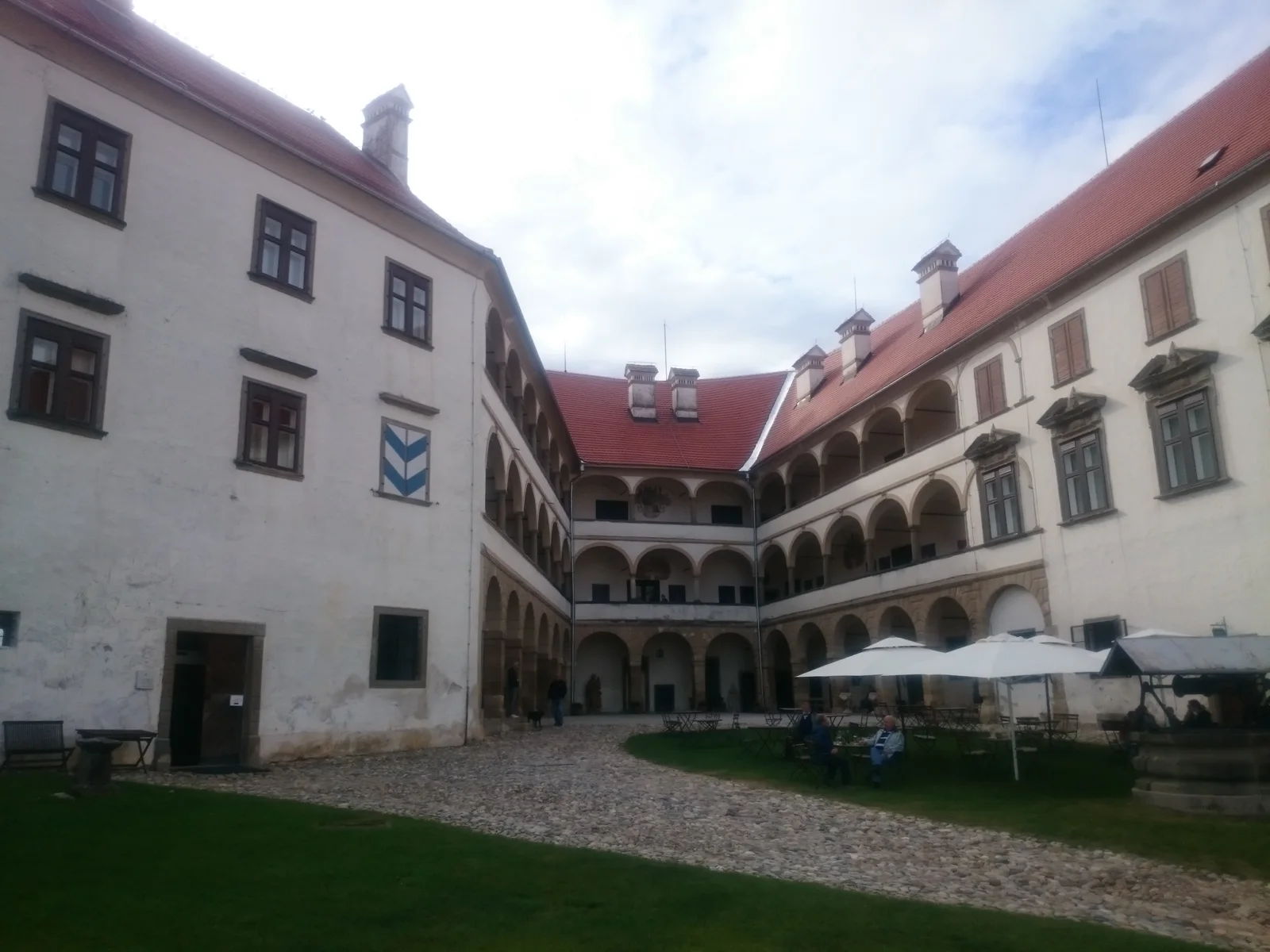Ptuj Castle's courtyard, arcaded galleries, red roofs and cobbled path.