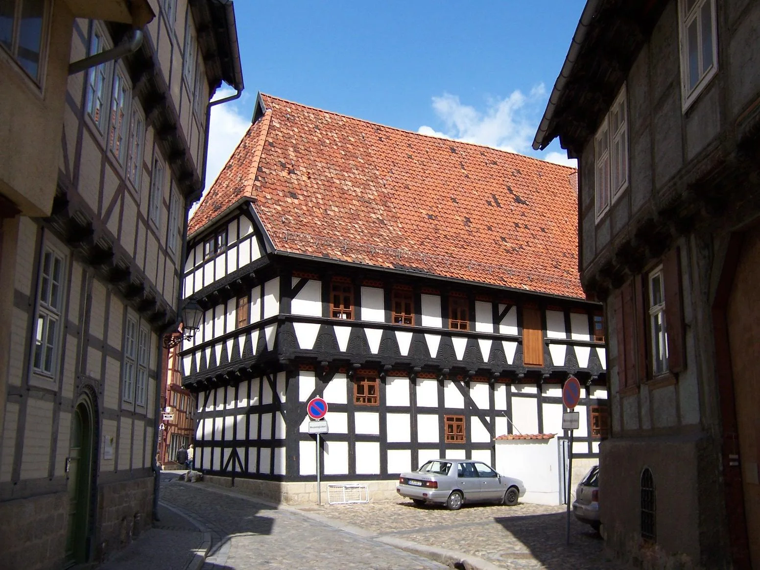 Black and white timber framing wraps around a house at the bend of a narrow cobbled lane.
