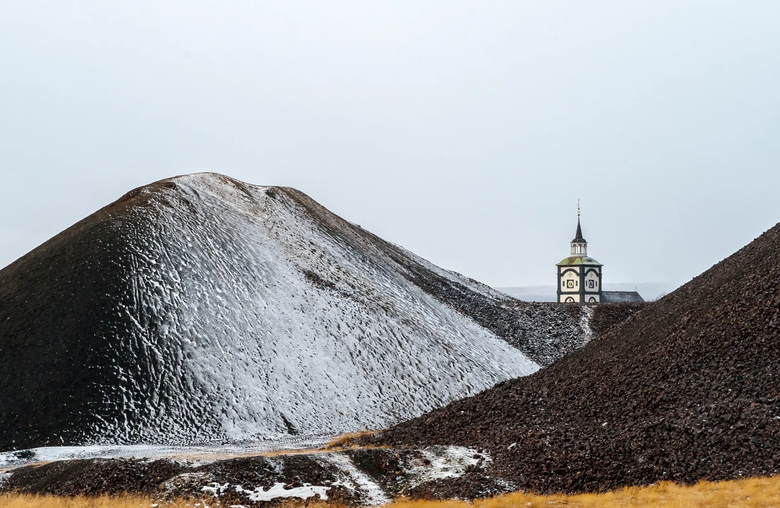 Snow-dusted slag heaps frame the distant clock tower of Røros Church.